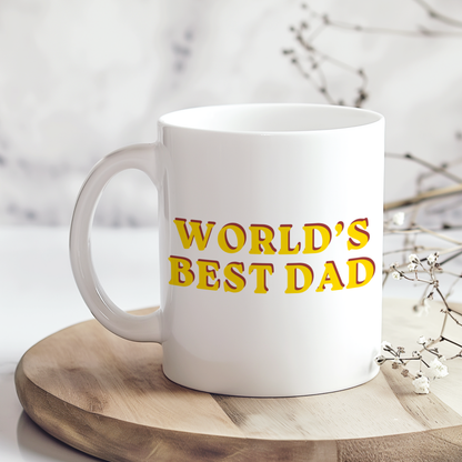 White ceramic mug with “WORLD’S BEST DAD” printed in bold retro yellow and red lettering, styled on a wooden board with a soft neutral background. Perfect Father’s Day or birthday gift for dads.