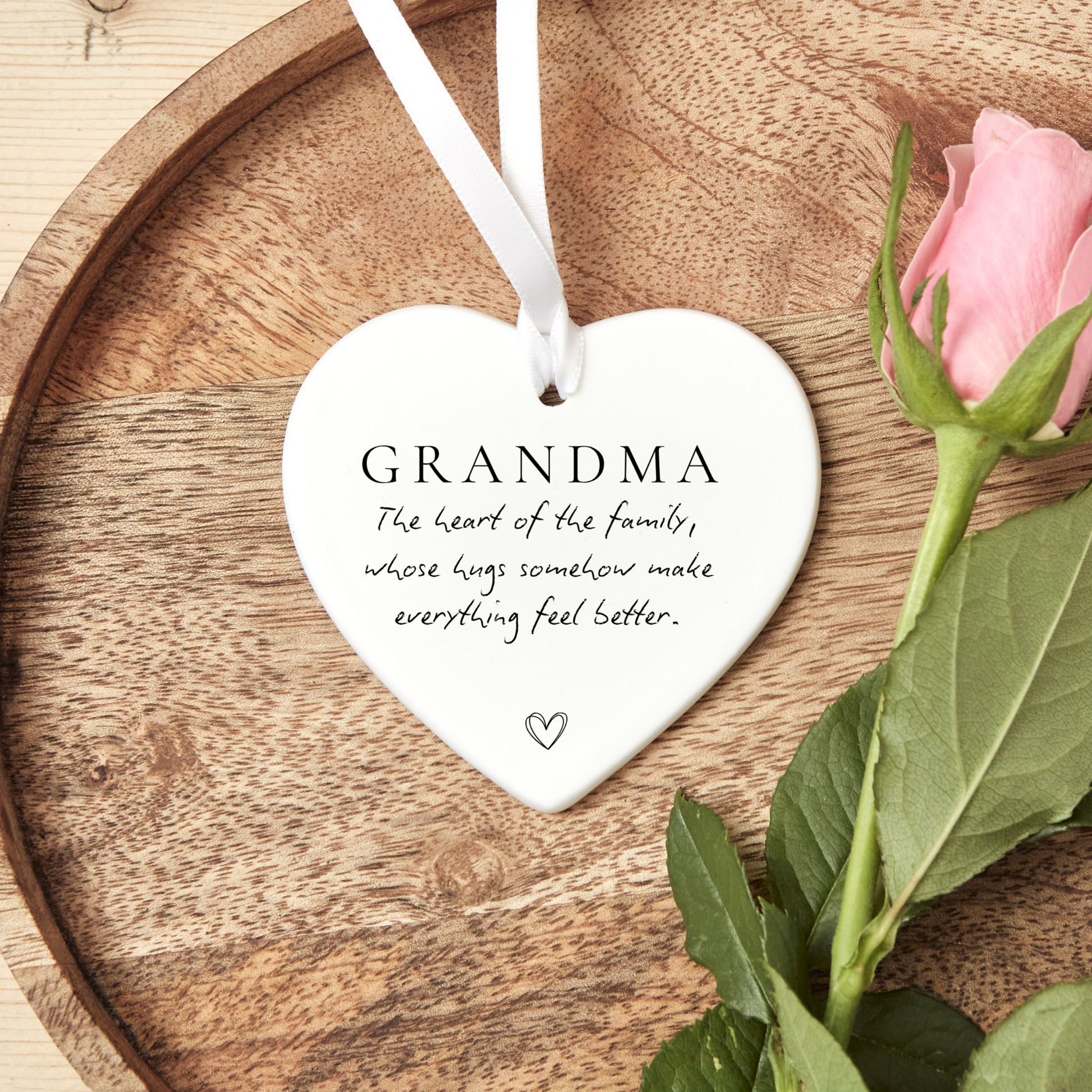 White ceramic Grandma Christmas ornament with ribbon featuring the quote “The heart of the family, whose hugs somehow make everything feel better”