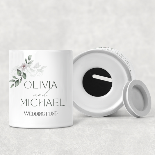 Personalised ceramic wedding fund money box with custom names and date, ideal engagement gift or bridal shower present, white pot with elegant lettering and heart detail.